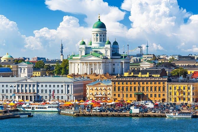 Photo of Helsinki. Several colorful buildings by a pier near the water.